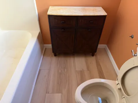 Finished bathroom: new flooring and trim around the tub, vanity and toilet