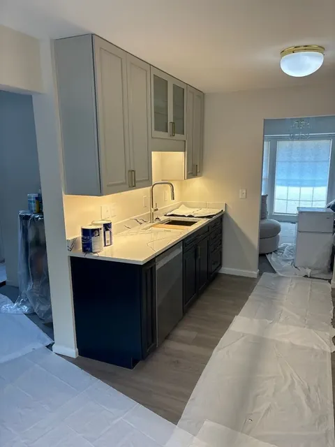 Kitchen after reconstruction: new grey and navy cabinets, white quartz counter and sink