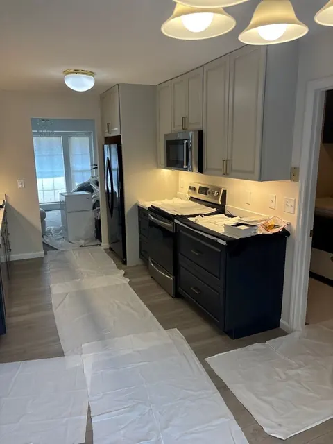 Rebuilt kitchen with new range, microwave and cabinets, floor protection still down